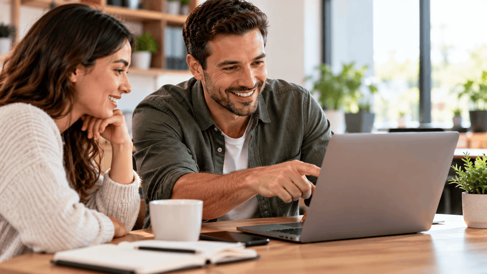 Smiling couple reviewing customer testimonials together on laptop at wooden desk