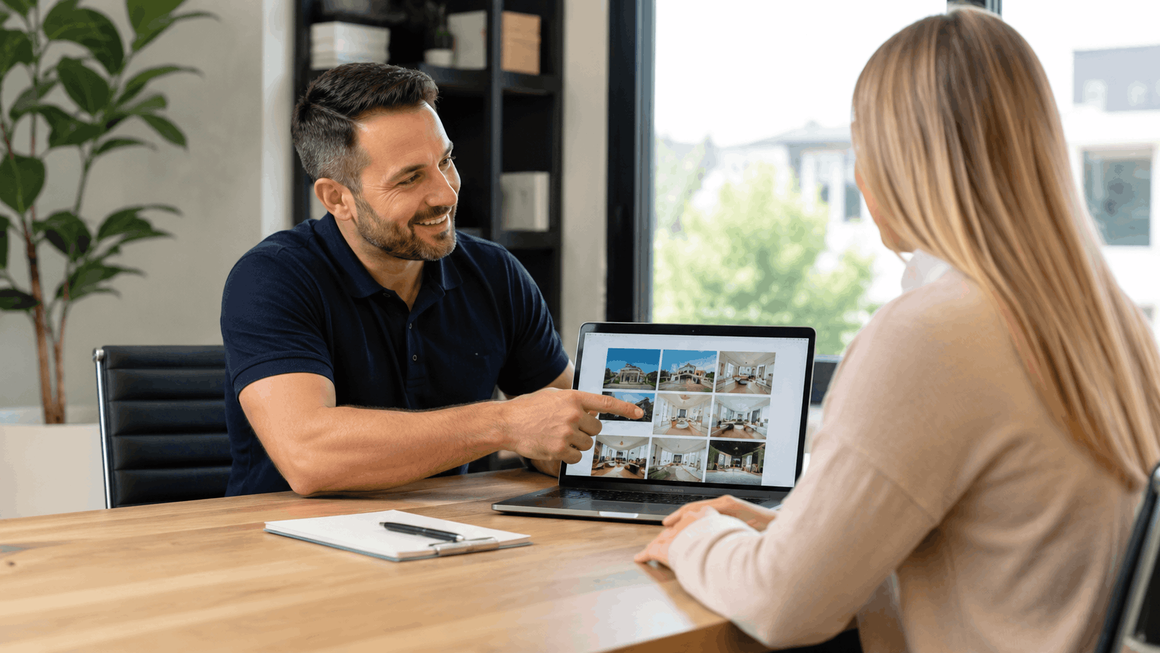Real estate agent showing property listings on laptop to female client in office