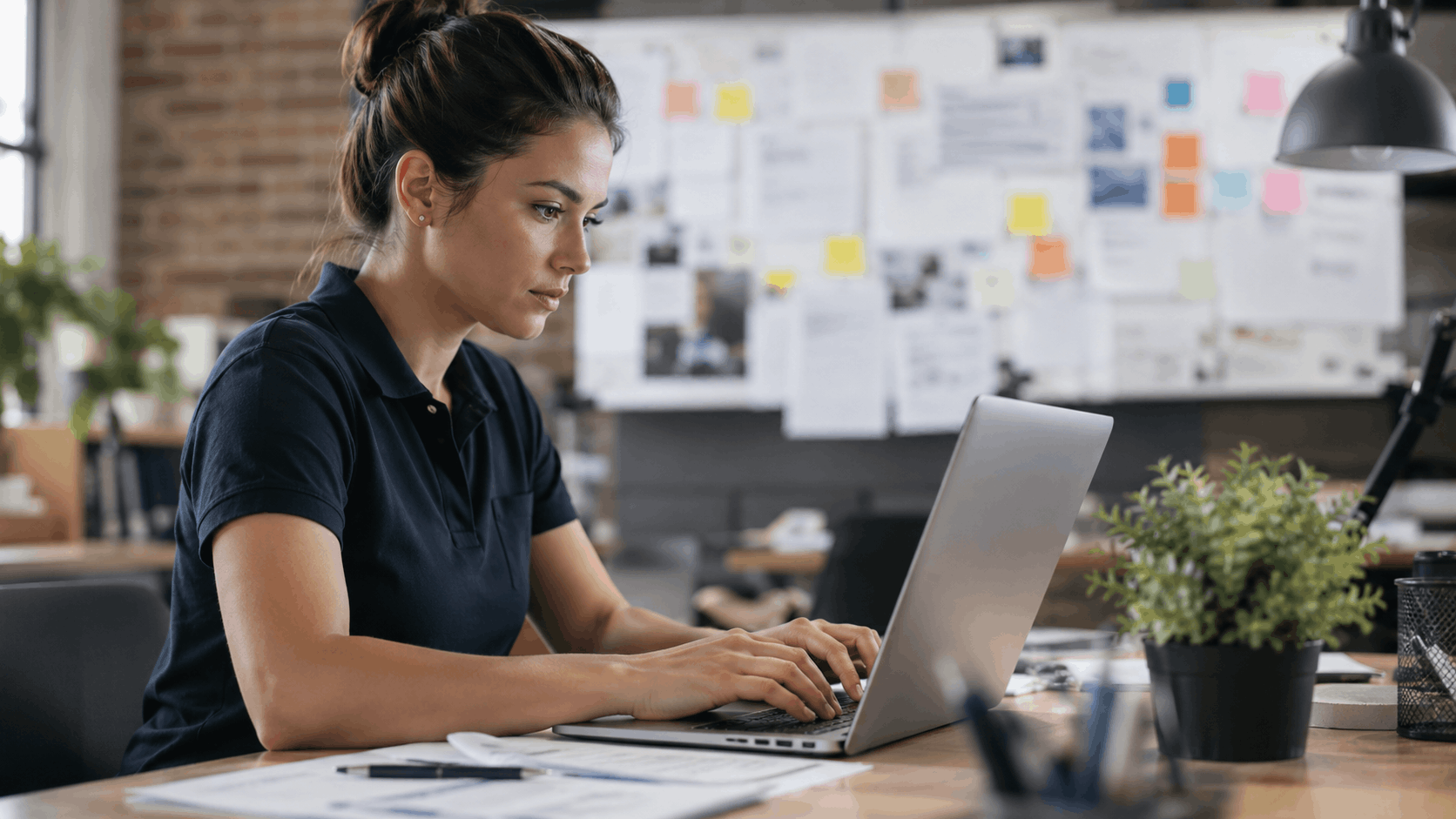 Woman working intently on laptop at desk in modern office workspace