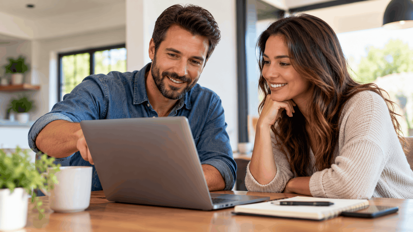Smiling couple reviewing online form together on laptop at home table