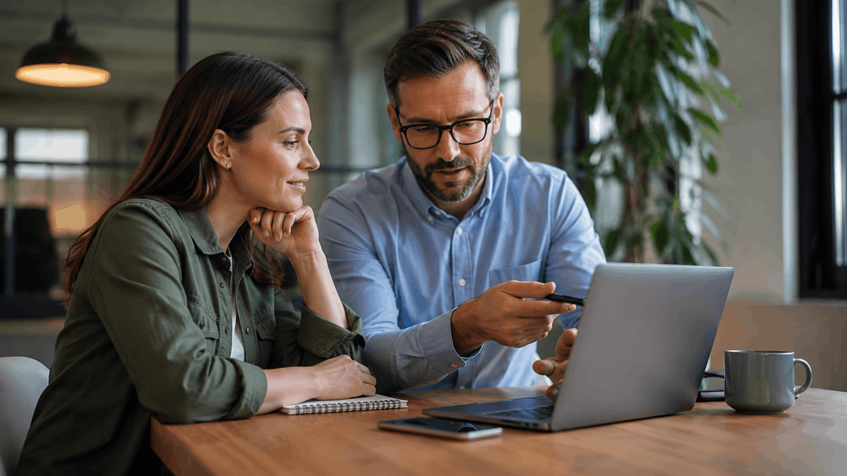 Two colleagues reviewing final project details together on a laptop in modern office