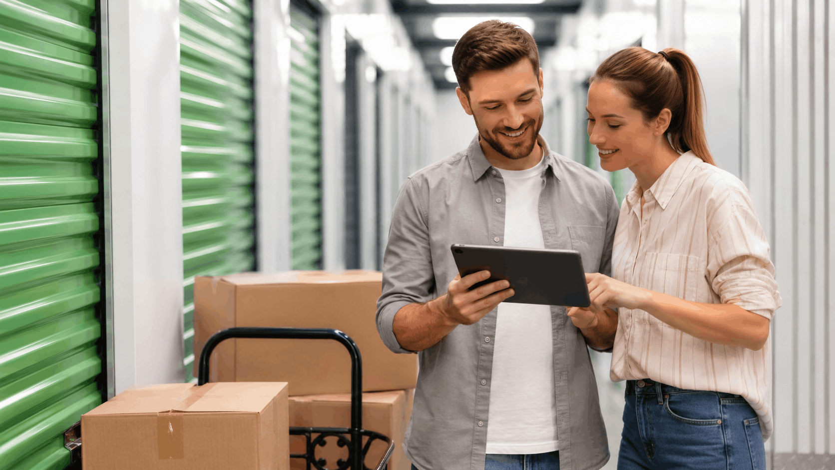Couple reviewing storage unit rental terms on tablet in self-storage facility hallway