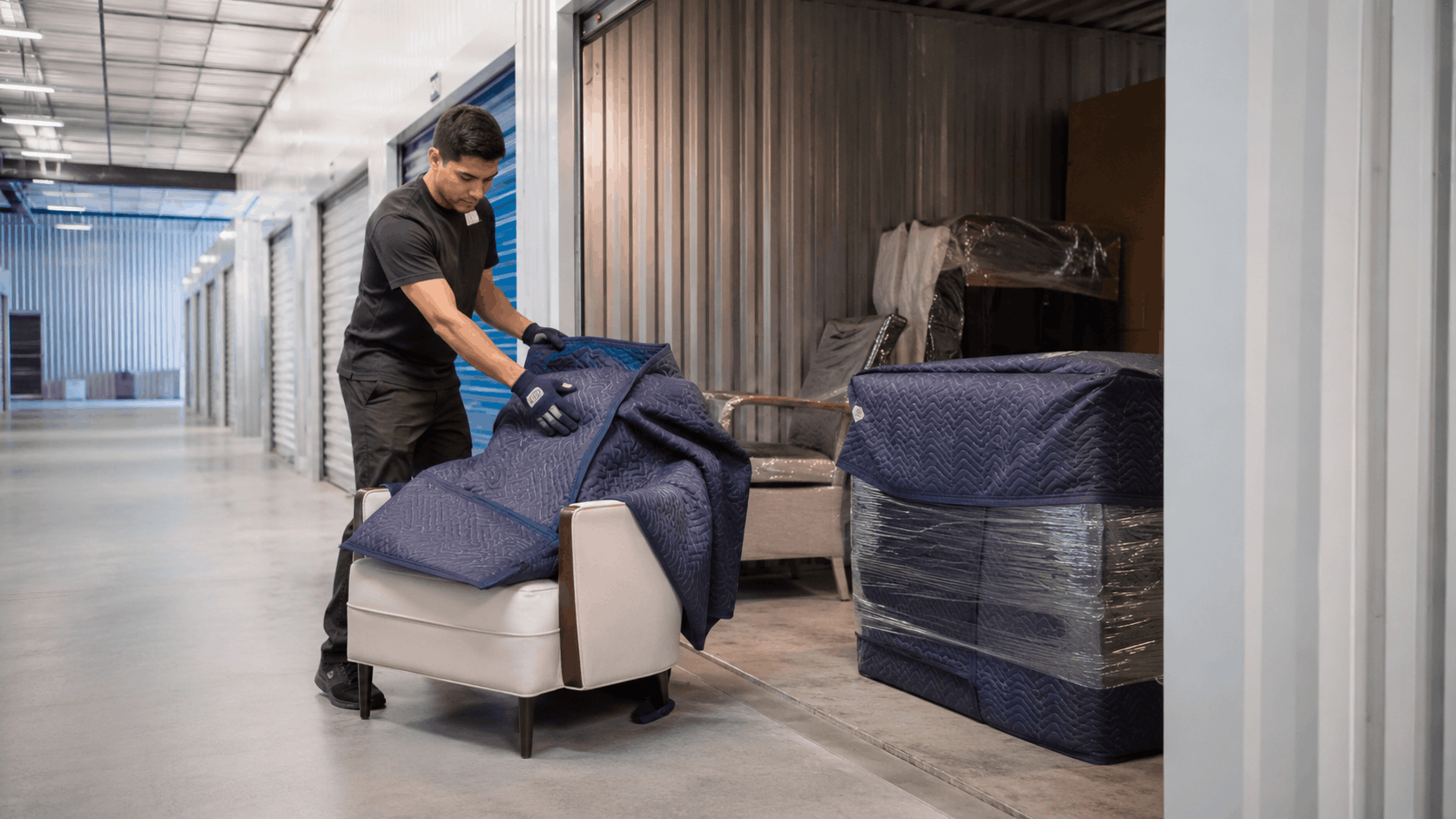 Popeye Moving worker wrapping armchair with moving blanket at Los Angeles storage unit