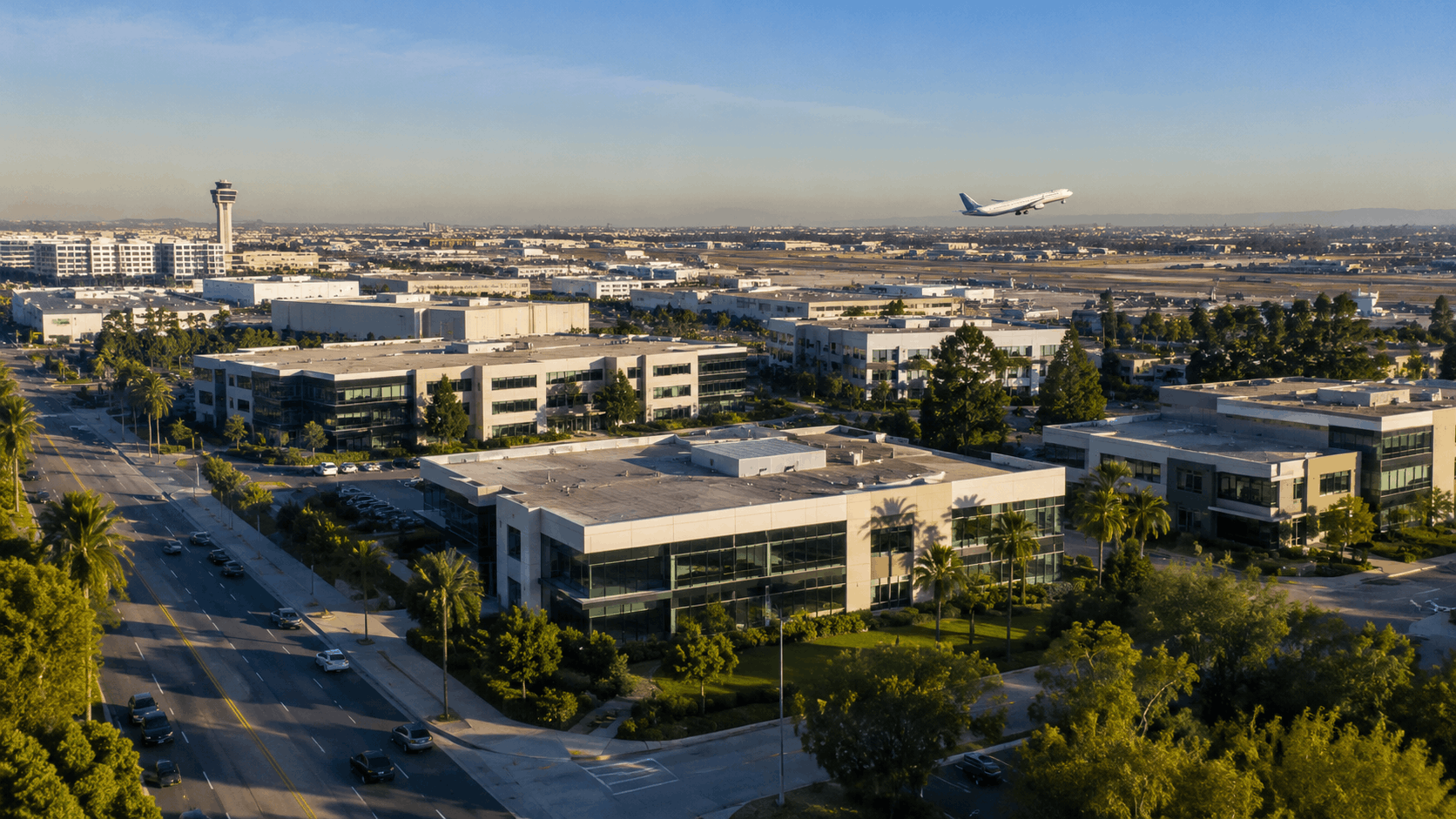 Aerial view of Los Angeles office buildings near LAX airport with departing airplane