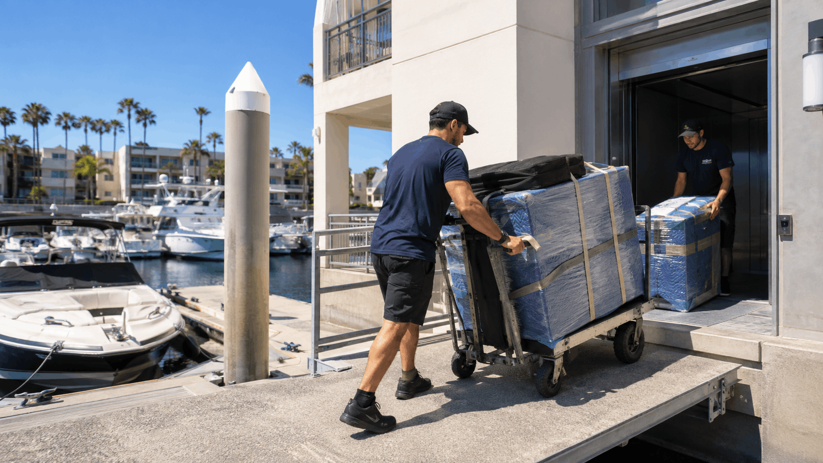 Two movers unloading wrapped furniture onto dolly at Marina del Rey waterfront building