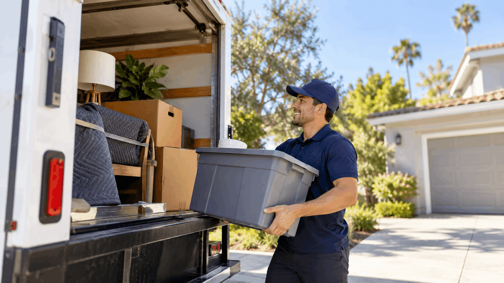 Professional Los Angeles mover loading gray storage bin into packed moving truck