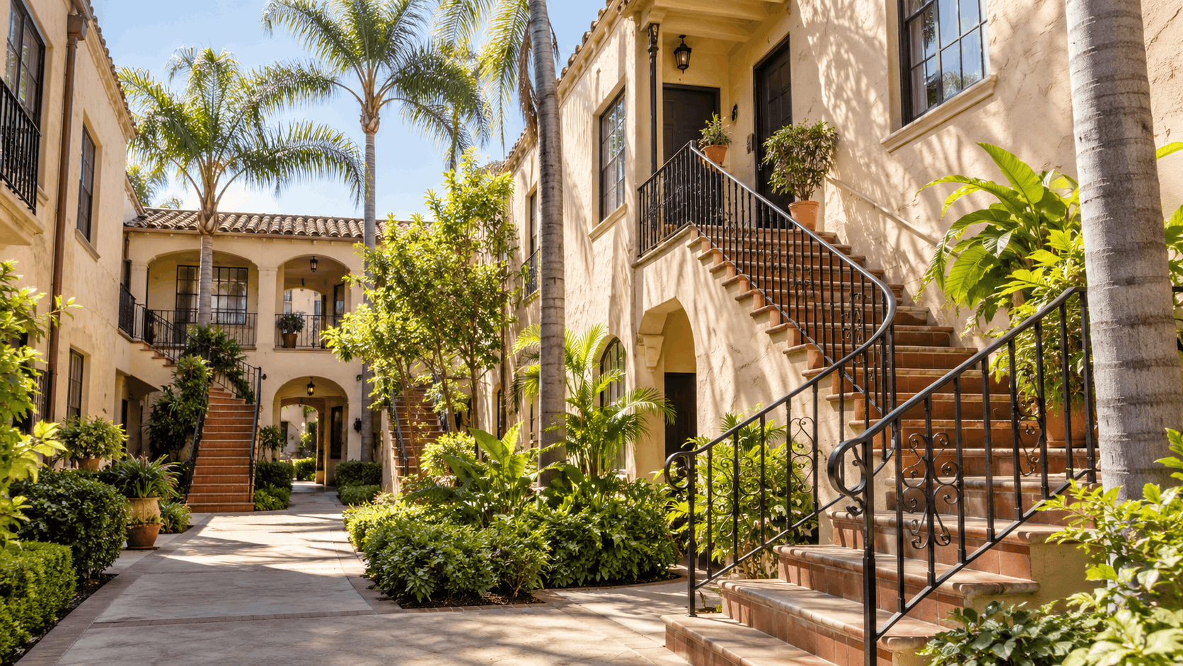 Spanish-style Los Angeles courtyard walk-up apartments with wrought iron staircases and palm trees