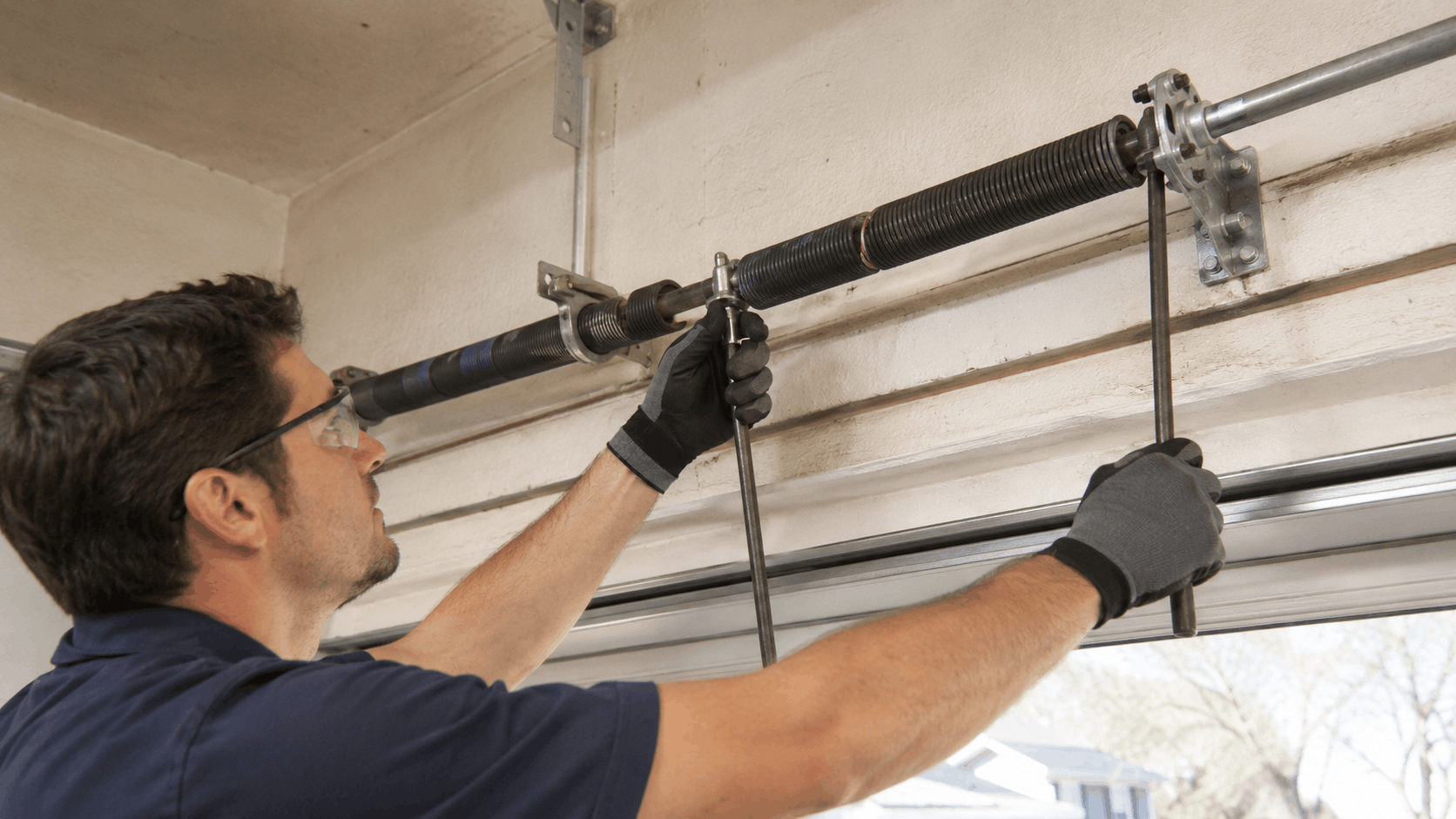 Technician repairing torsion springs on a 1990s-era garage door in Irvine