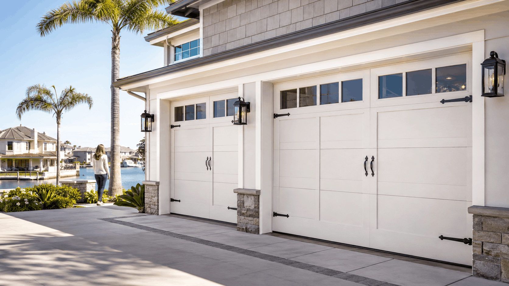 White carriage-style garage doors on luxury Irvine waterfront home with palm trees