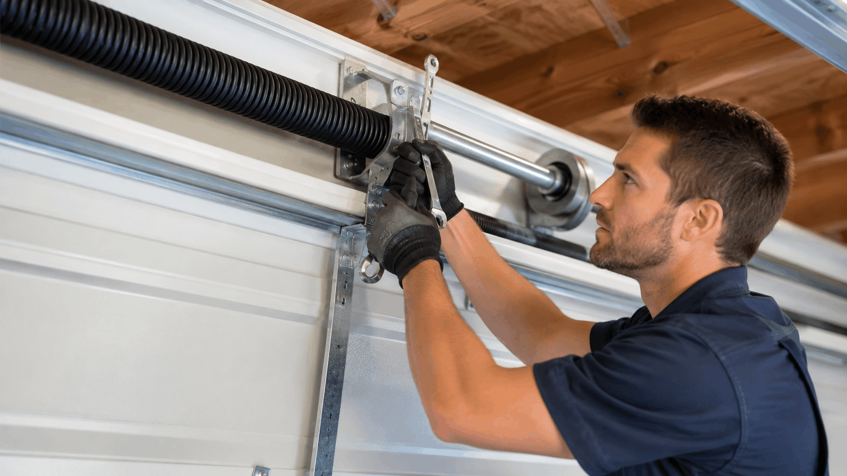 Technician repairing torsion spring system on white sectional garage door