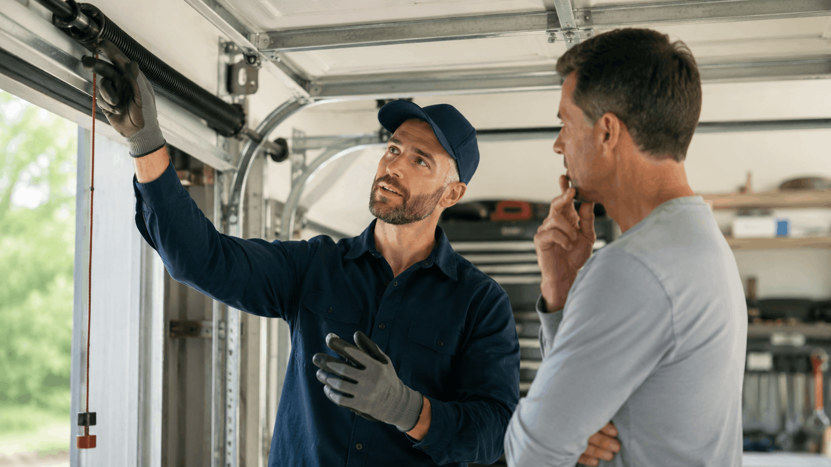 Garage door technician explaining torsion spring repair to Irvine homeowner during inspection