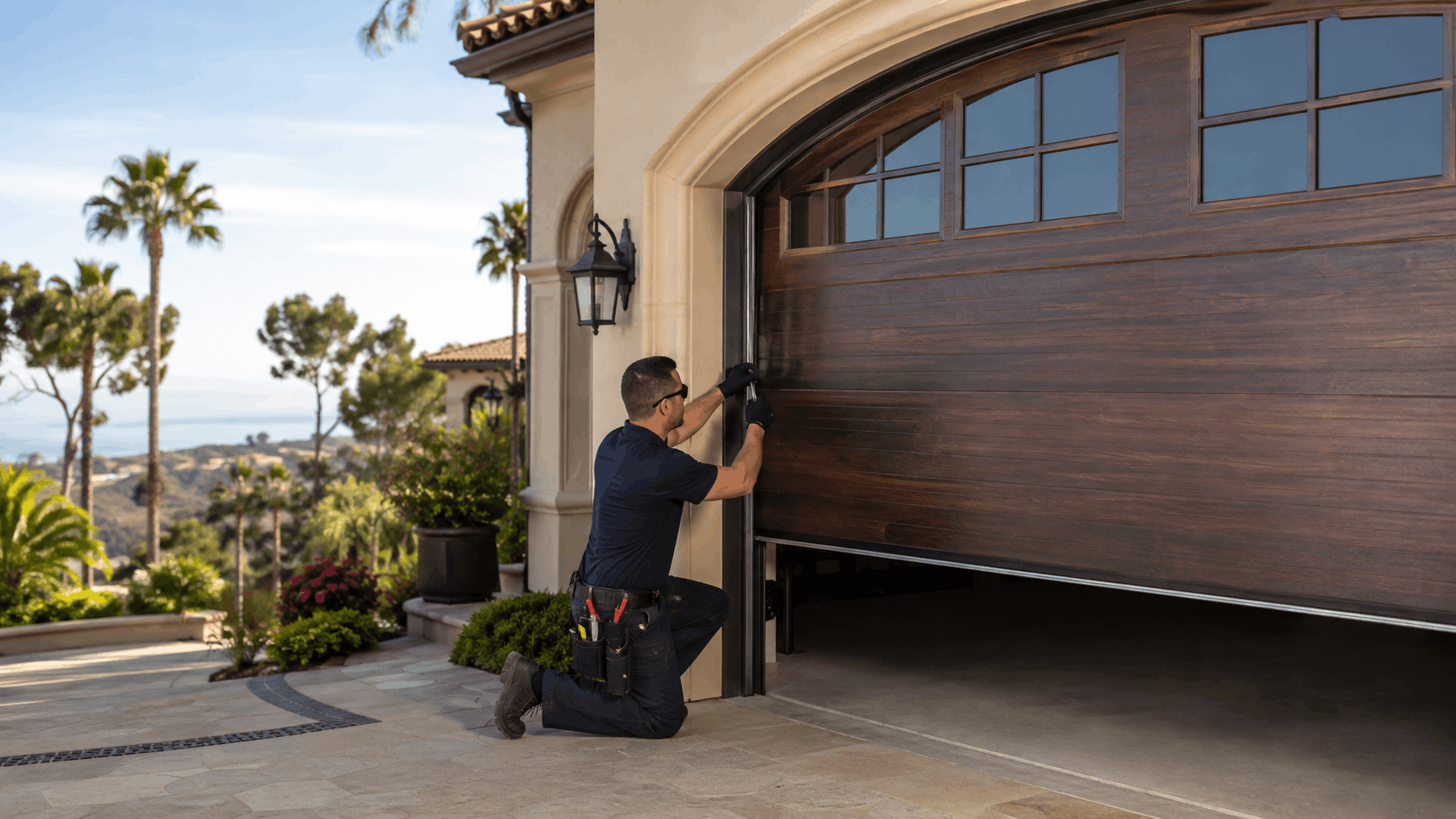Garage door technician kneeling to repair wooden garage door at luxury Irvine home