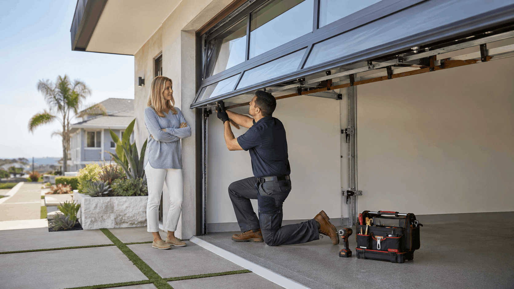 Garage door technician repairing residential glass panel door while homeowner watches in Irvine