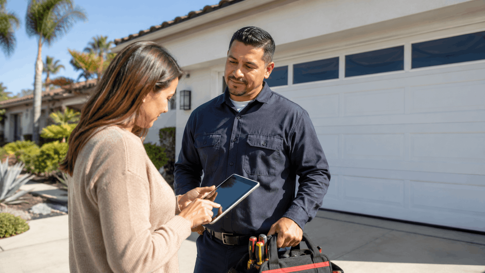 Homeowner reviewing contractor license verification on tablet with garage door technician in Irvine