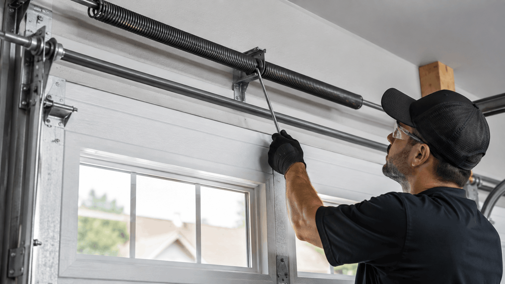 Garage door technician adjusting torsion spring system with winding bar in Irvine
