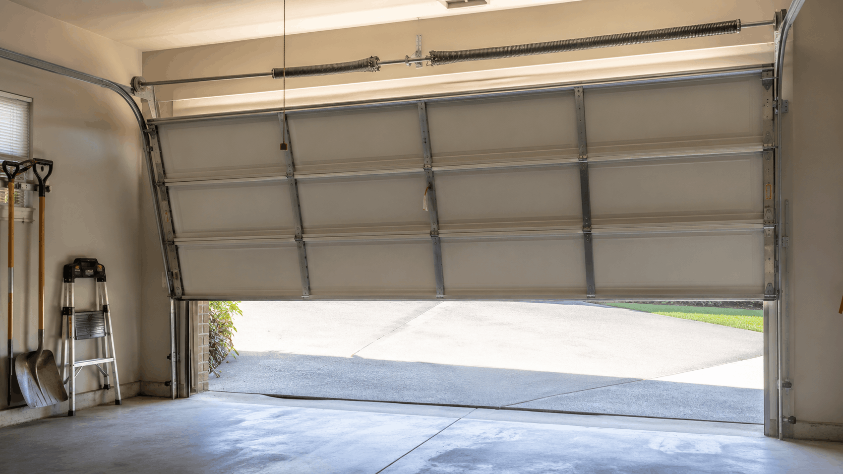Garage door with torsion spring system partially open showing interior tracks and hardware