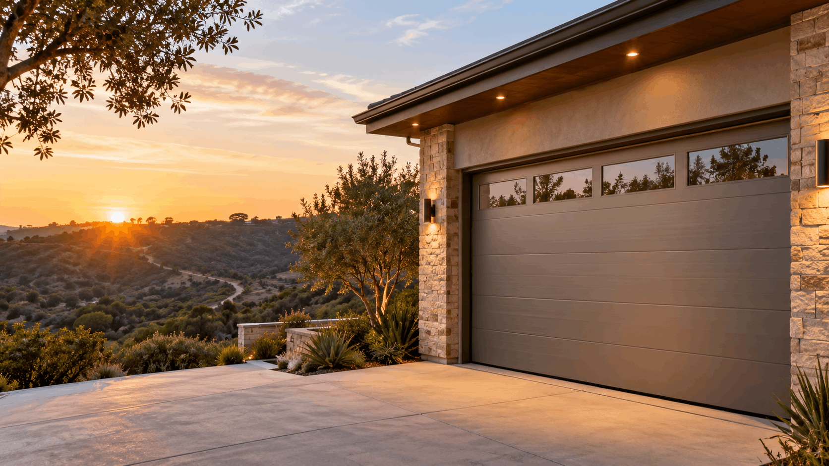Modern tan garage door with windows on hillside home at golden sunset