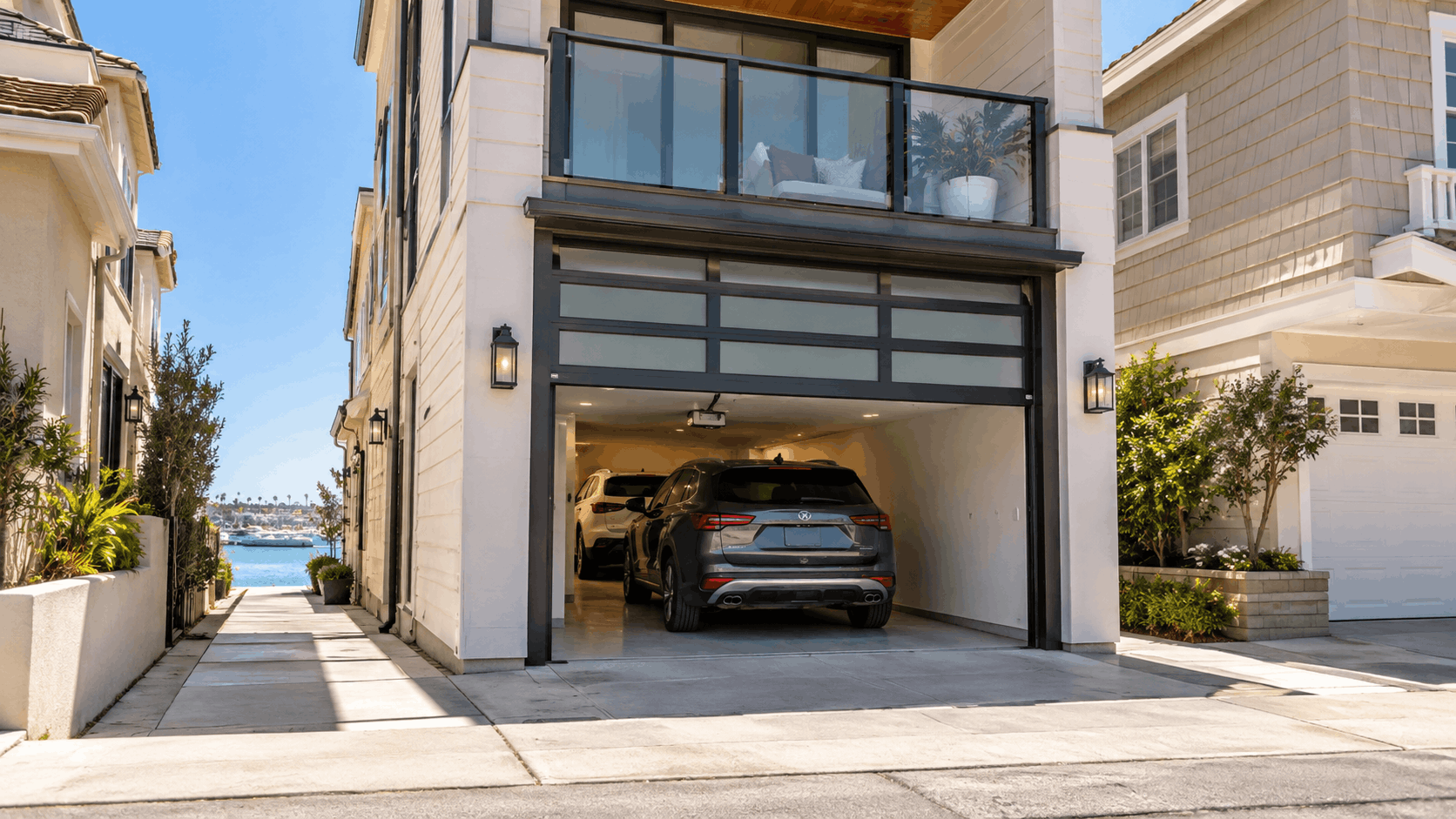 Modern glass panel garage door open revealing two SUVs in Newport Beach Peninsula home